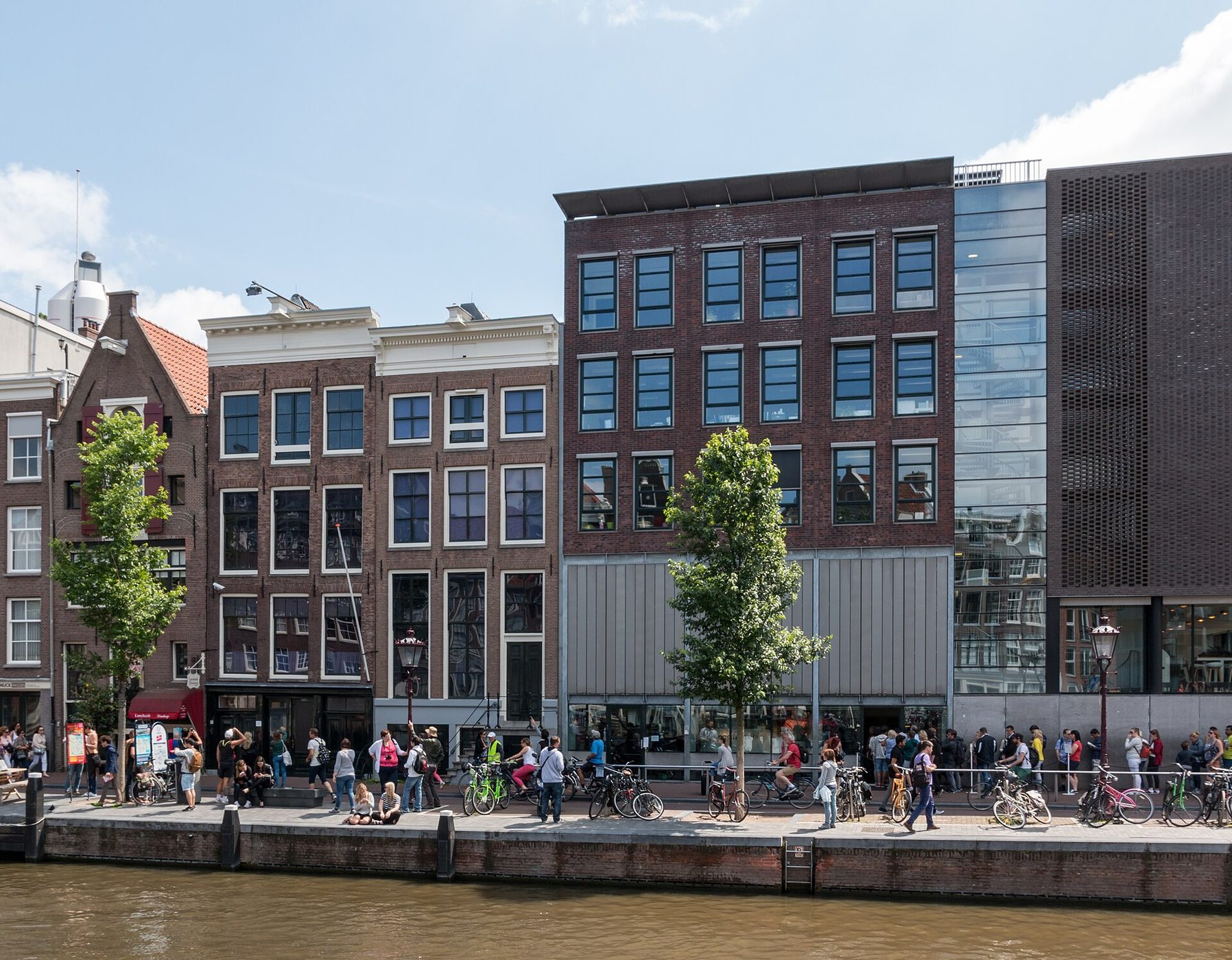 Brick canal houses of the Anne Frank House on Prinsengracht in Amsterdam, with visitors and cyclists along the quay