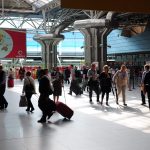 Travellers with suitcases walking through the main hall of Terminal 1 at Lisbon Humberto Delgado Airport