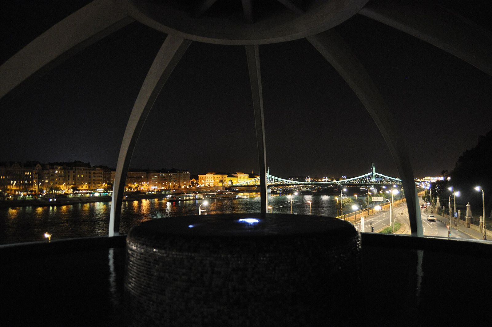 The Rudas Bath panorama pool at night, looking across the Danube to the lit Pest riverbank and a bridge